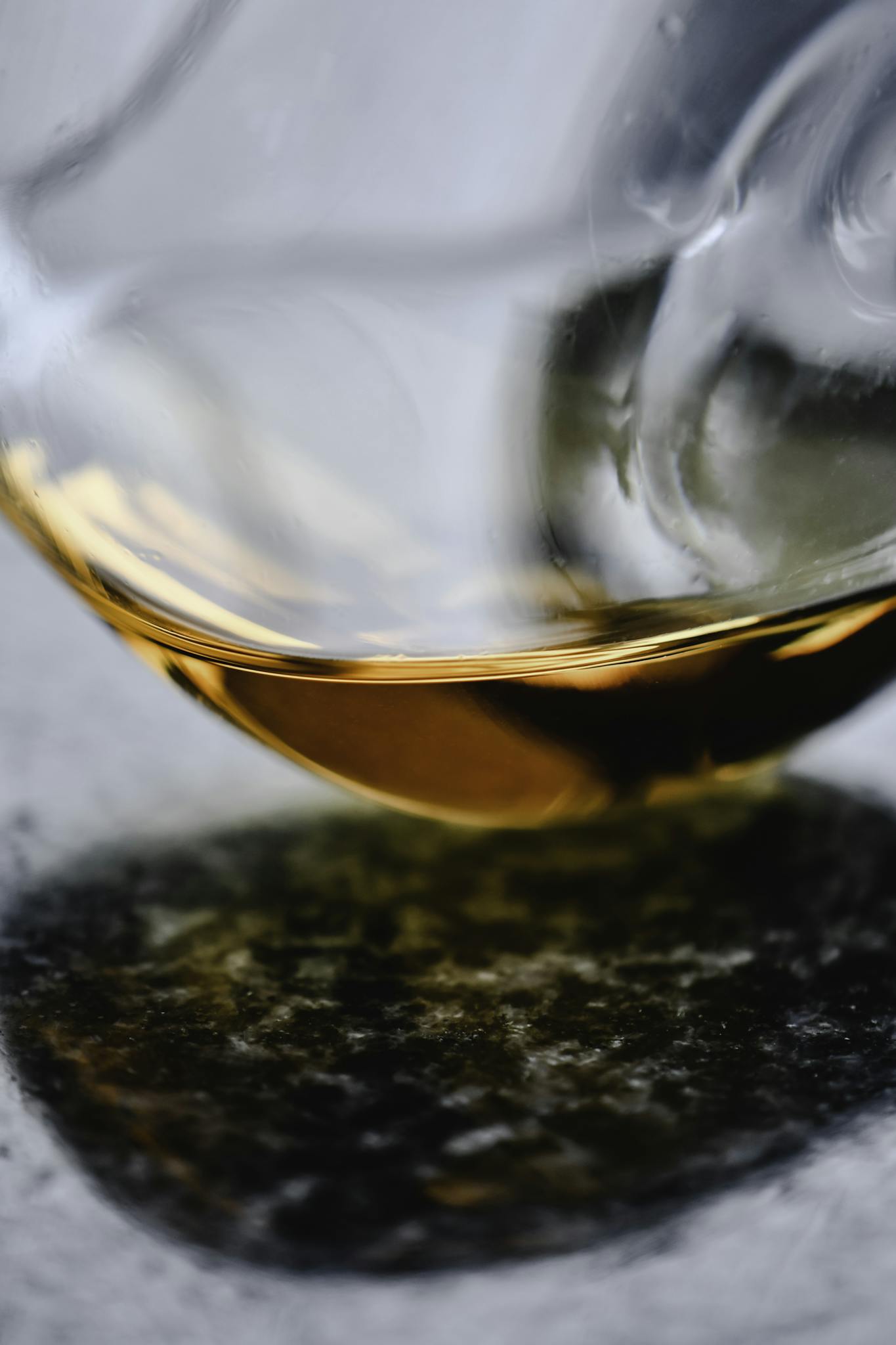 Artistic close-up of cognac in a curved glass reflecting on a marble surface.